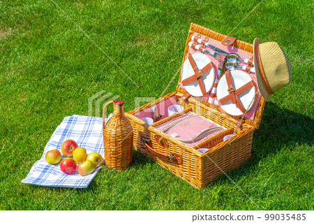 Weekend Picnic straw basket on green sunny lawn in the park 99035485