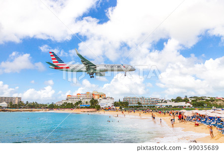 PHILIPSBURG, SINT MAARTEN - DECEMBER 13, 2016: A commercial airplane approaches Princess Juliana airport above onlooking spectators on Maho beach. PHILIPSBURG, SINT MAARTEN - DECEMBER 13, 2016: A commercial airplane approaches Princess Juliana airport above onlooking spectators on Maho beach. 99035689