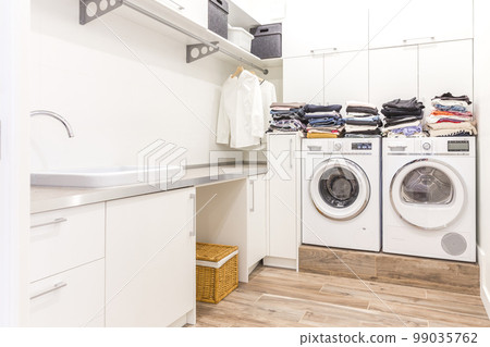 Piles of clean clothes in laundry room 99035762
