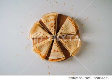 Flat lay of crepes laid out in triangles in a circle on a wooden board Flat lay of crepes laid out in triangles in a circle on a wooden board 99036350