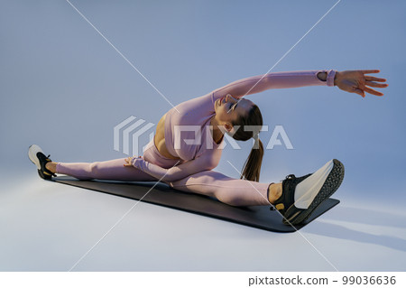 Flexible woman doing stretching exercises on yoga mat on studio background. Healthy lifestyle 99036636