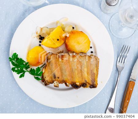 Stylishly served plate of tasty pork ribs with some potatoes 99037404