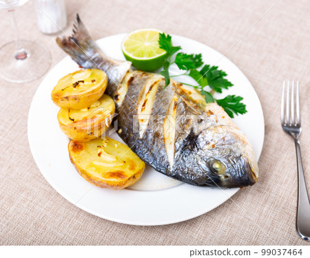 Cooked dorada served on plate with herbs lime and potatoes on the side Cooked dorada served on plate with herbs lime and potatoes on the side 99037464