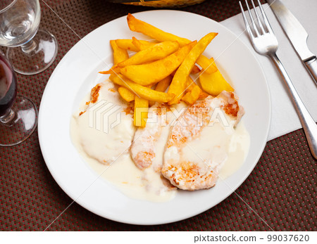 Appetizing carve pork topped with creamy sauce and cheese served french fried potato Appetizing carve pork topped with creamy sauce and cheese served french fried potato 99037620