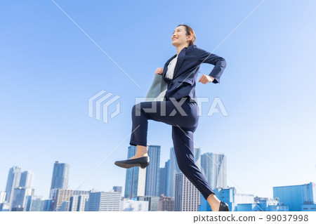 Career woman running in a suit in the city 99037998