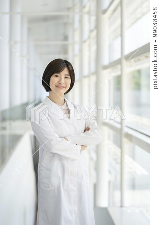 A smiling young woman in a white coat looking at the camera portrait 99038458