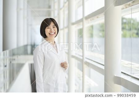 A smiling young woman in a white coat looking at the camera portrait 99038459