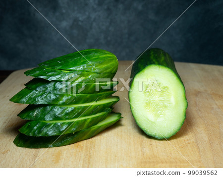 A smooth, medium-sized cucumber cut into slices. Cucumber on a cutting board. Vegetable isolate. Fresh ripe vegetable A smooth, medium-sized cucumber cut into slices. Cucumber on a cutting board. Vegetable isolate. Fresh ripe vegetable 99039562