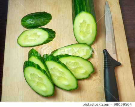 A smooth, medium-sized cucumber cut into slices. Cucumber on a cutting board. Vegetable isolate. Fresh ripe vegetable A smooth, medium-sized cucumber cut into slices. Cucumber on a cutting board. Vegetable isolate. Fresh ripe vegetable 99039564