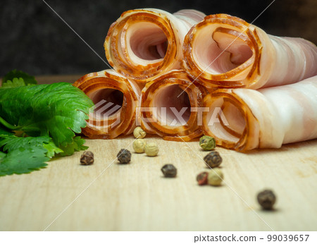 Curvy cut folded into rolls. Pork on a kitchen board with parsley. Still life of meat. Curvy cut folded into rolls. Pork on a kitchen board with parsley. Still life of meat. 99039657