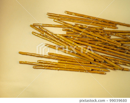 Salted sticks. Confectionery on the table. Salty baked goods. Snack for beer. Dough product on a beige background. Not a healthy diet 99039680