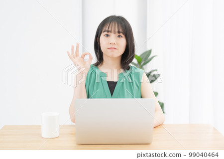 一位年輕女子在電腦前做出 OK 的手勢 一位年輕女子在電腦前做出 OK 的手勢 99040464