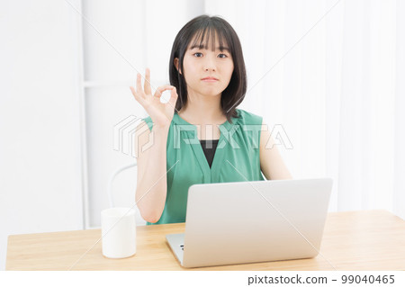 一位年輕女子在電腦前做出 OK 的手勢 一位年輕女子在電腦前做出 OK 的手勢 99040465