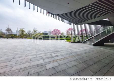Empty brick floor and modern building in city park with green tree background 99040697