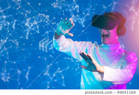 Asian man in white long sleeve t- shirt wearing vr goggles headset, watching, playing, touching and connecting with virtual reality world game on blue background. Metaverse and Technology concept.. Asian man in white long sleeve t- shirt wearing vr goggles headset, watching, playing, touching and connecting with virtual reality world game on blue background. Metaverse and Technology concept.. 99041169