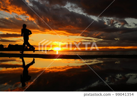 The silhouette of a young man running on the beach at sunset on the Zushi coast The silhouette of a young man running on the beach at sunset on the Zushi coast 99041354