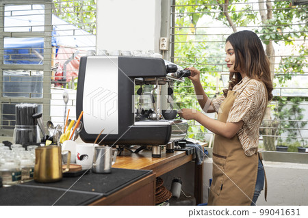 Asian woman barista making coffee by machine 99041631