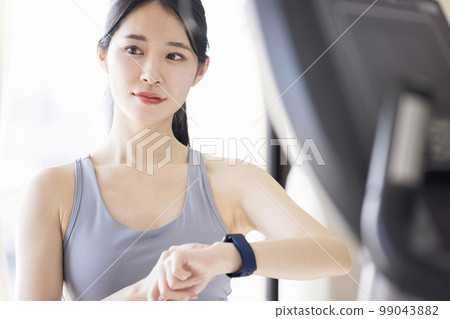 在健身房操作智能手錶的年輕女性 在健身房操作智能手錶的年輕女性 99043882