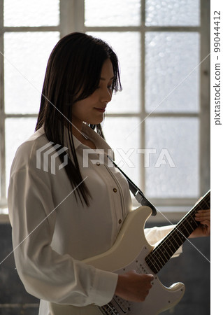 Young woman portrait (backlit, electric guitar) 99044412