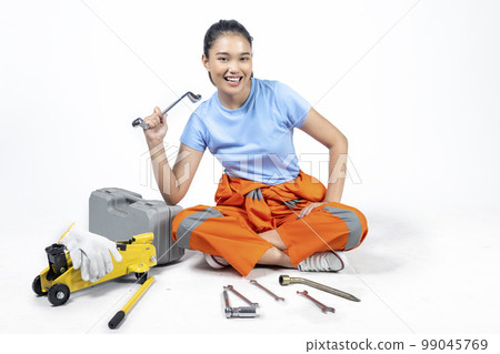 Asian woman car technician in uniform sitting with a car jack and toolkit box and wrench 99045769