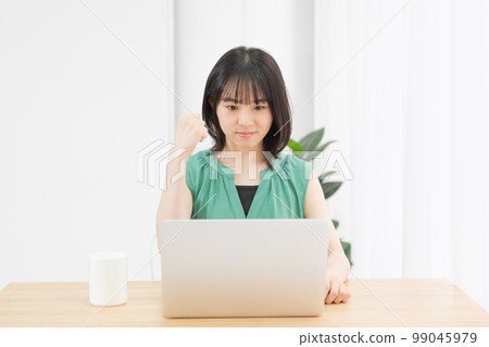 A young woman doing a guts pose in front of a PC A young woman doing a guts pose in front of a PC 99045979