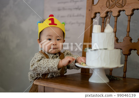 baby eating cake on 1st birthday 99046139