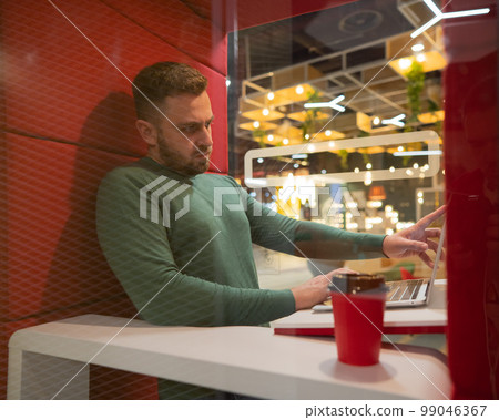 A bearded man in a booth for online negotiations. Privacy booth. A bearded man in a booth for online negotiations. Privacy booth. 99046367