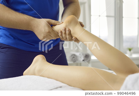 Masseur massage patient foot in saloon 99046496