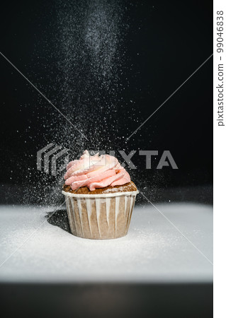 Cupcake on a dark background, which is sprinkled on top. Cupcake on a dark background, which is sprinkled on top. 99046838