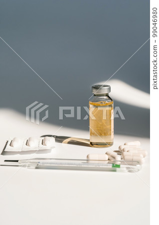 Medicines and a thermometer lie on the white surface of the table. 99046980