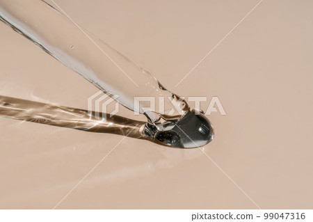 A drop of cosmetic oil falls from the pipette 99047316