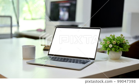Laptop white screen mockup is on a modern office desk. close-up image 99047398