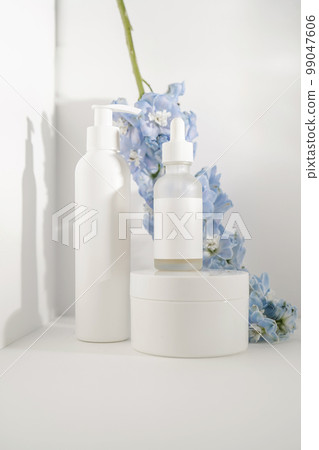 Cosmetic bottles and flowers on a white background. Cosmetic bottles and flowers on a white background. 99047606