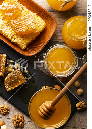 Honeycomb on slate tray with honey and nuts on kitchen table 99048342
