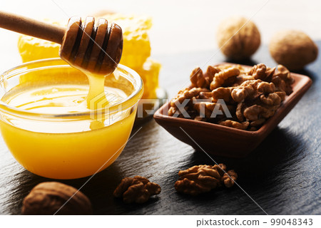 Slate tray with honey walnuts and honeycomb on kitchen table 99048343