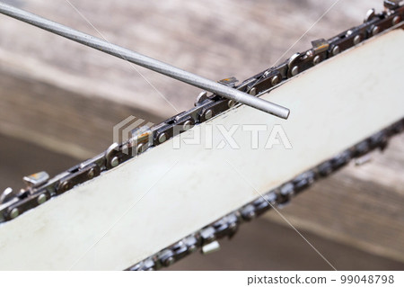chainsaw chain sharpening with a special file. Dulling an old chain on a chainsaw bar. Industry 99048798