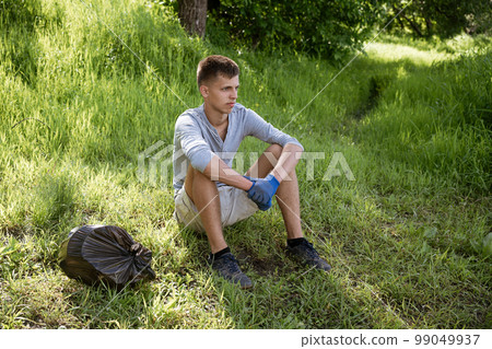young man resting after cleaning the park young man resting after cleaning the park 99049937