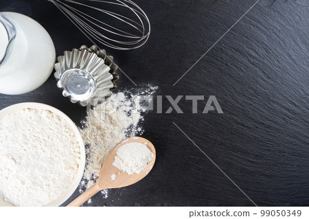 Baking ingredients flour, eggs, milk, bakeware on black slate background with copy space Baking ingredients flour, eggs, milk, bakeware on black slate background with copy space 99050349