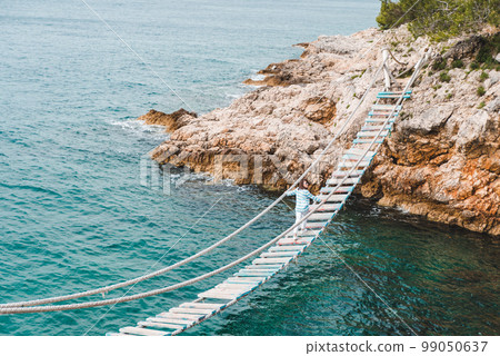 woman crossing suspension bridge sea on background woman crossing suspension bridge sea on background 99050637