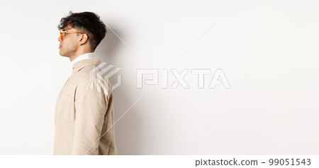 Profile of handsome caucasian man in eyewear, looking at empty space left with serious face, standing on white background 99051543