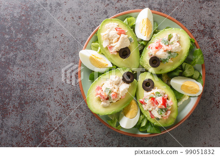 Tasty Palta Reina is a popular Chilean starter with peeled avocado stuffed with chicken salad closeup on the plate. Horizontal top view 99051832