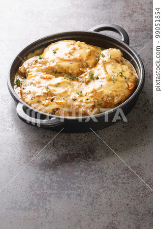Creamy smothered pork chops seared and cooked in a rich onion gravy closeup on the pan. Vertical 99051854