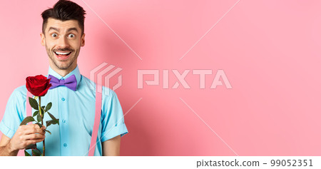 Excited bearded man with moustache and bow-tie waiting for date with red rose, having romantic moment on Valentines day, standing on pink background Excited bearded man with moustache and bow-tie waiting for date with red rose, having romantic moment on Valentines day, standing on pink background 99052351