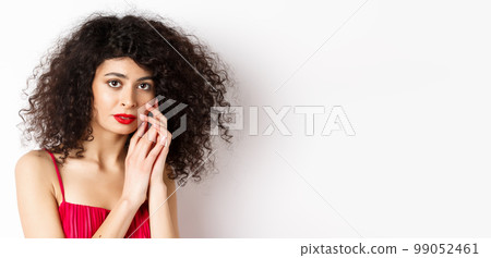 Close-up of tender romantic woman, gently touching face and looking sensual at camera, white background Close-up of tender romantic woman, gently touching face and looking sensual at camera, white background 99052461