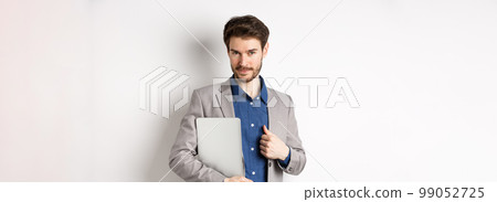 Successful businessman in stylish suit carry laptop and looking confident at camera, smiling pleased, white background 99052725