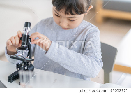 Elementary school girl operating a microscope 99052771