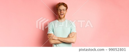 Portrait of cheerful european man in glasses looking amazed at camera, see interesting promotion, standing amused over pink background 99052801