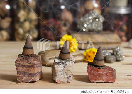 Incense Cones and Chakra Stones With Flowers in Background Shallow DOF Incense Cones and Chakra Stones With Flowers in Background Shallow DOF 99052973