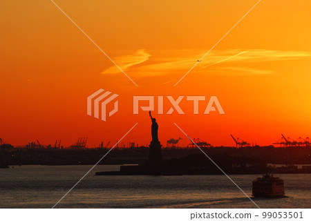 Silhouette of Statue of Liberty and Liberty Island in New York against an orange sunset sky Silhouette of Statue of Liberty and Liberty Island in New York against an orange sunset sky 99053501