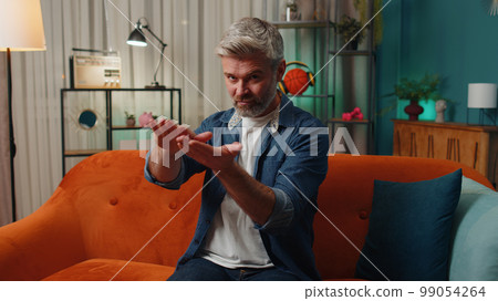 Rich happy old man showing wasting or throwing money around hand gesture, profit win lottery, share 99054264